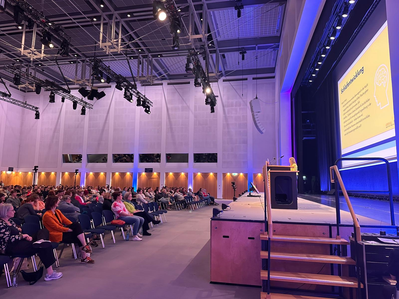 Janine May spricht vor vollem Saal im Congress Center Leipzig